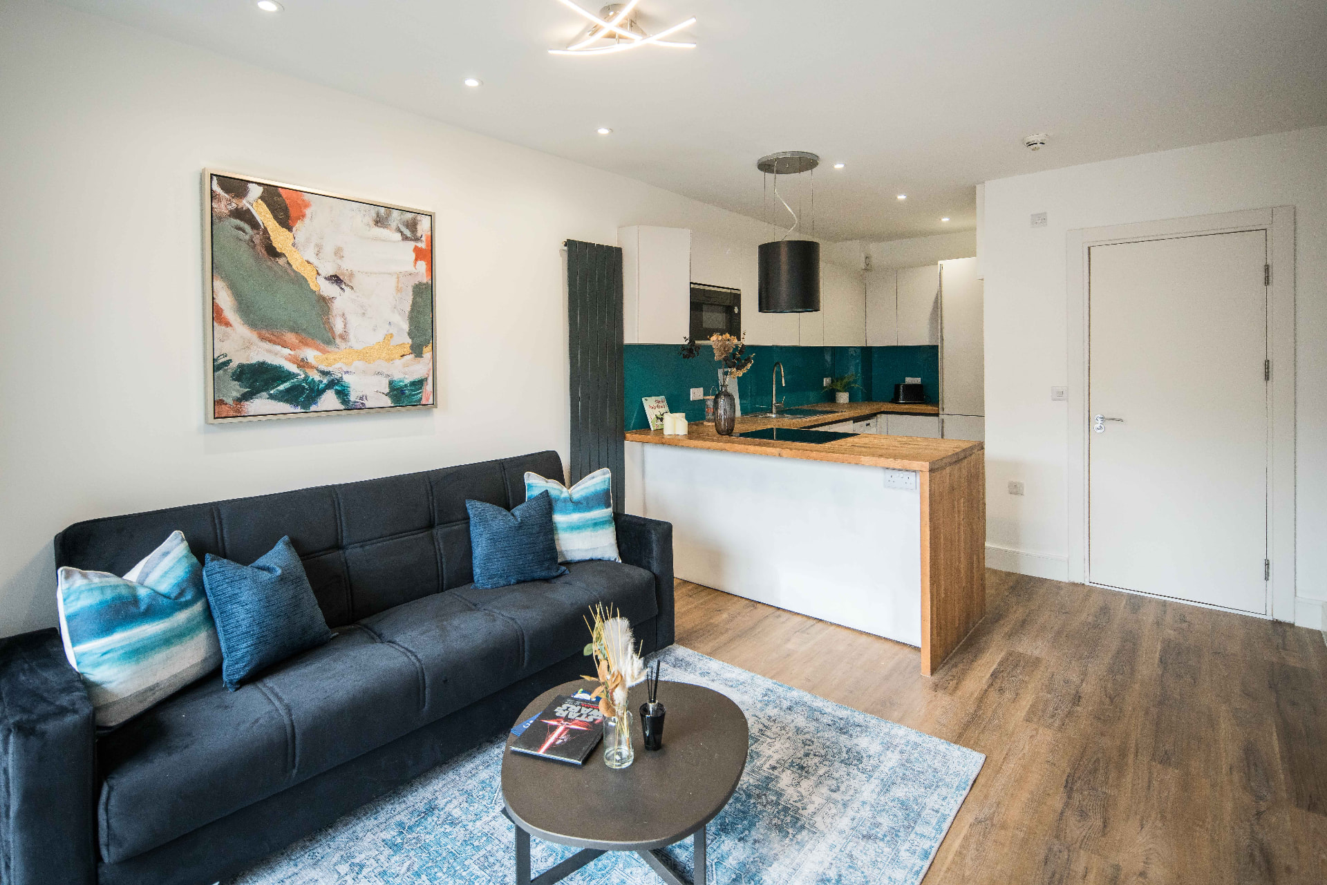 Open-plan living area with a sofa and a kitchen island with a wooden worktop.